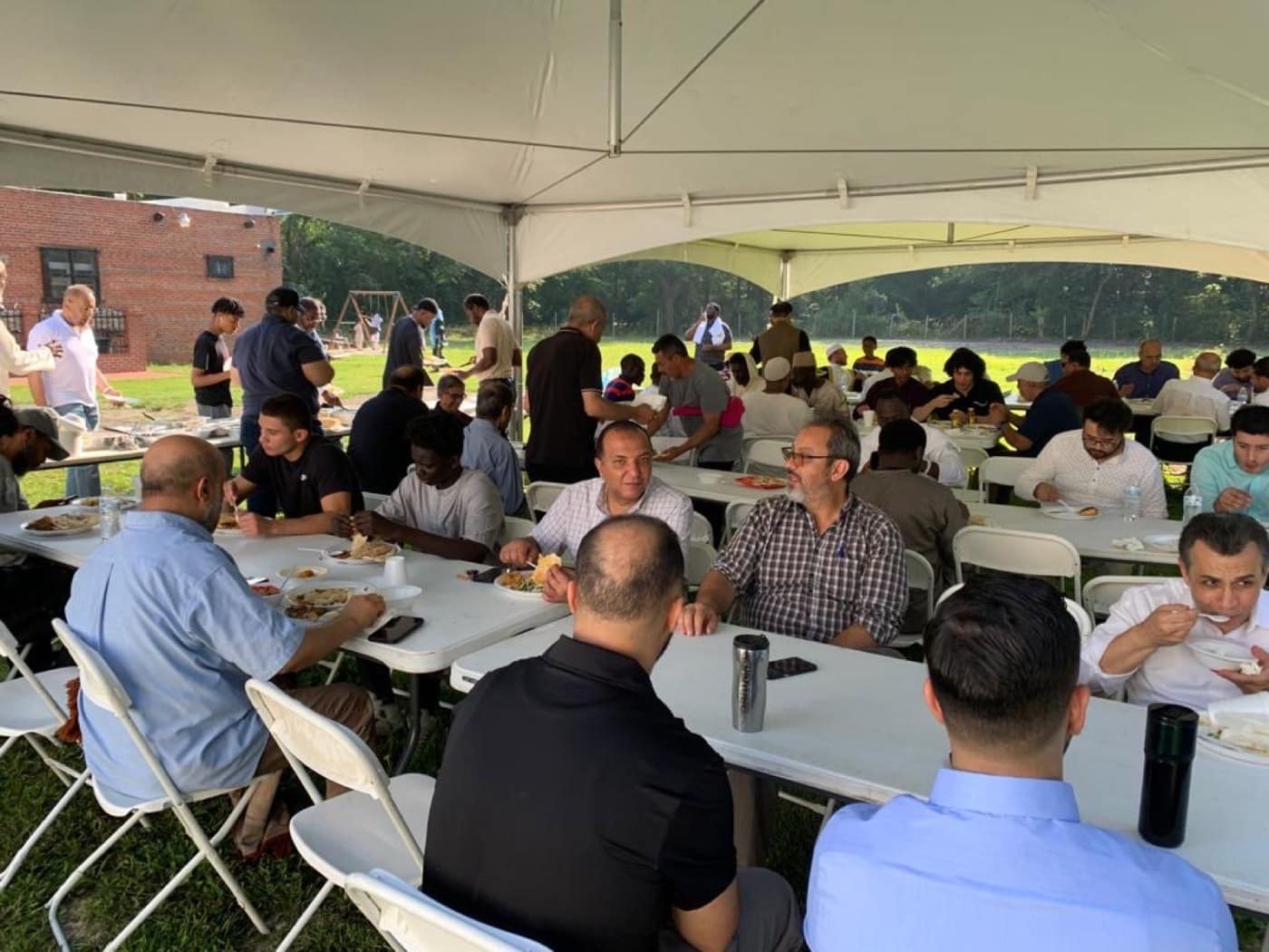 The congregation sharing a meal under a marquee on the lawn