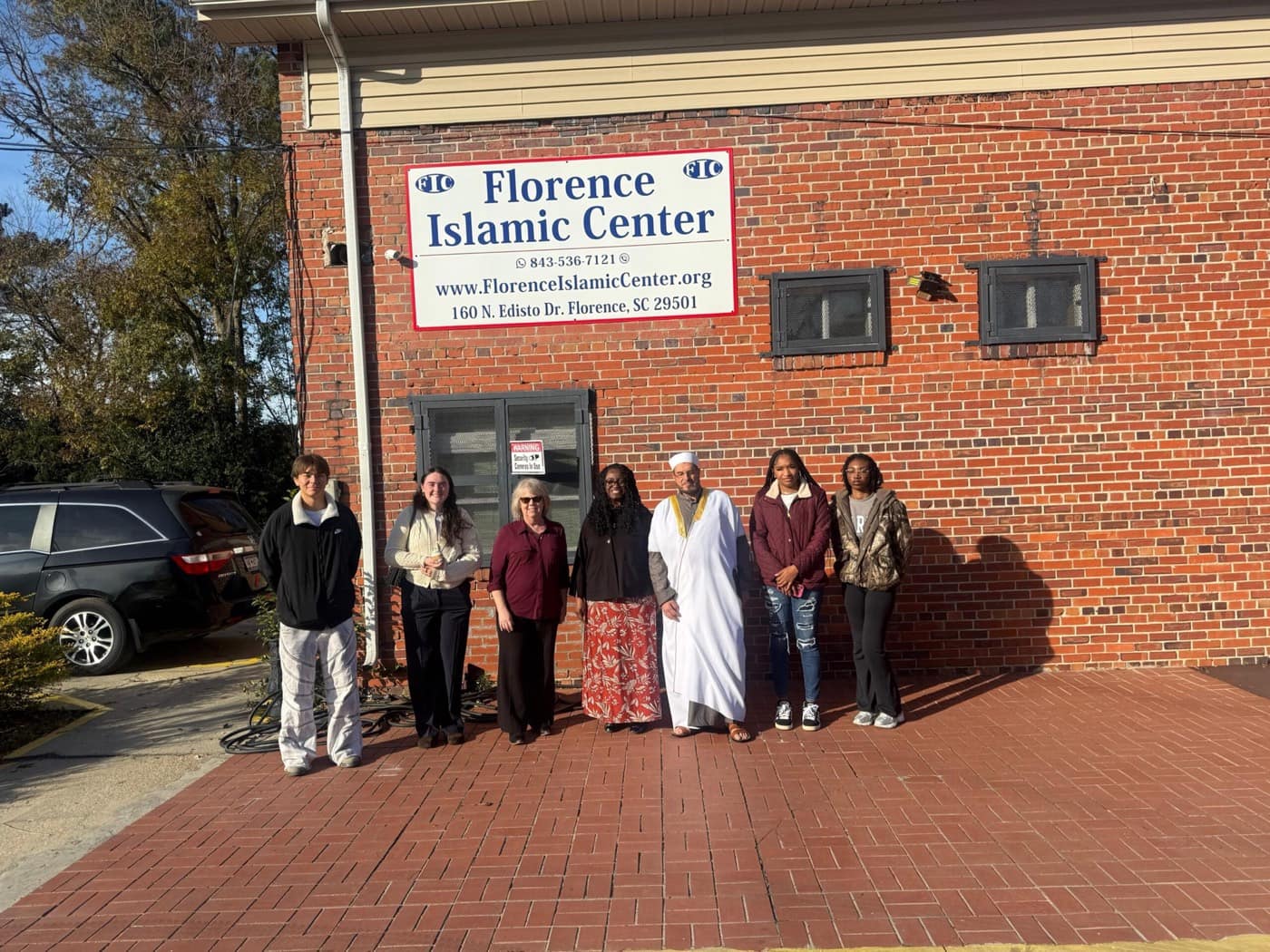 The Imam and a group of visitors under the Florence Islamic Center sign